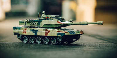 Grøn Battle Tank Metal LE fjernstyret kampvogn med metalkomponenter kører gennem mudret terræn i naturen.