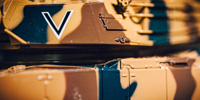 Grå Battle Tank Metal Limited Edition fjernstyret kampvogn kører gennem mudret terræn i naturen.