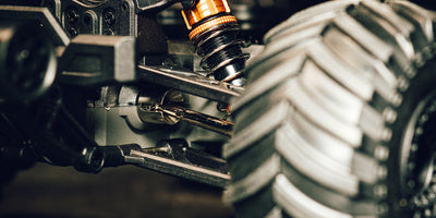 Hurricane XL brushless monster truck i fuld fart gennem terrænet på en støvet grusvej.