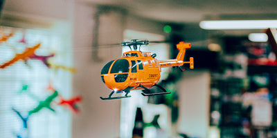 Grå C186 helikopter med single-rotor og fire blade vist fra siden på en hvid baggrund.