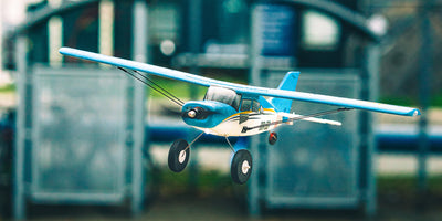 Gult QIDI-560 Brushless sportsfly i flot flyvning lavt over en grøn mark i dagslys.