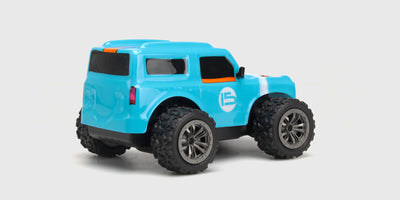 Blå Rapid Monster Truck med orange detaljer og store terrængående dæk til børn vist på hvid baggrund.