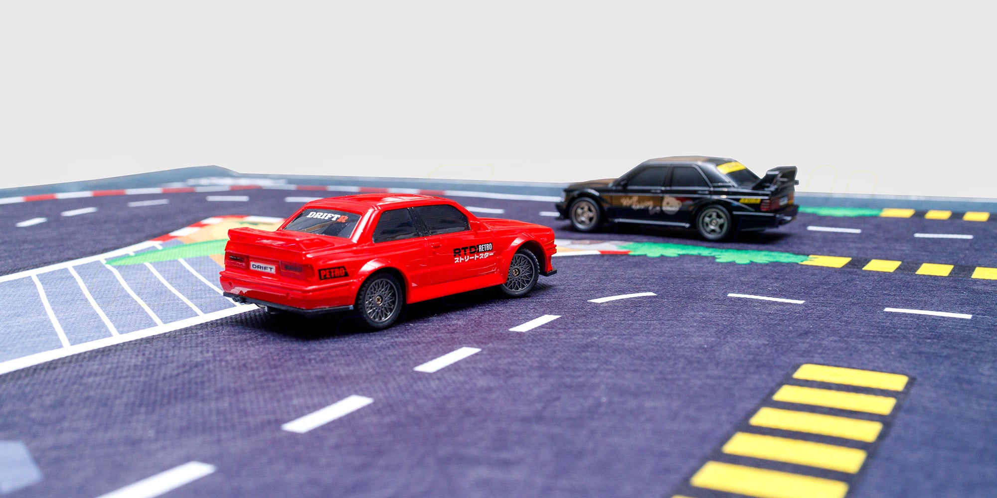 Gråt racerbane tæppe med vejbaner og parkeringspladser til leg med fjernstyrede biler.