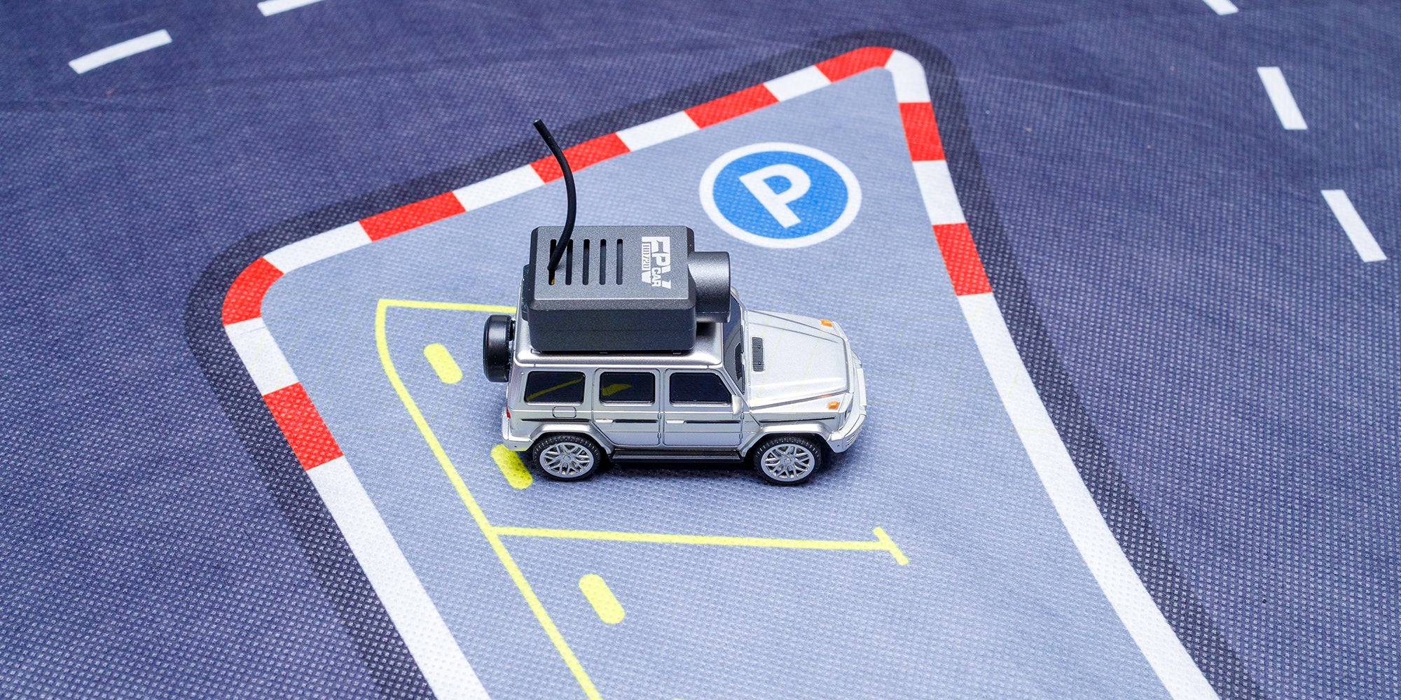 Gråt racerbanetæppe med hvide banemarkeringer rulles ud til kørsel med fjernstyrede biler.