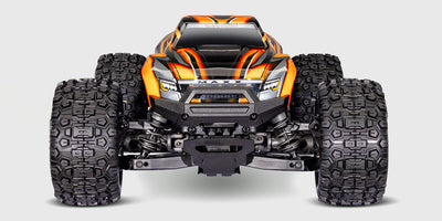 Traxxas Mini Maxx fjernstyret bil i orange med store offroad-hjul vist fra siden på en hvid baggrund.