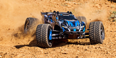 Blå Traxxas Rustler 4x4 Ultimate fjernstyret bil med offroad-dæk vist skråt forfra på hvid baggrund.