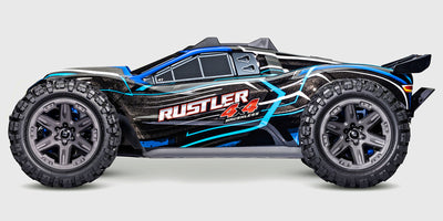Blå Traxxas Rustler 4x4 BL-2S fjernstyret stadium truck vist i fuld fart på en grusvej.