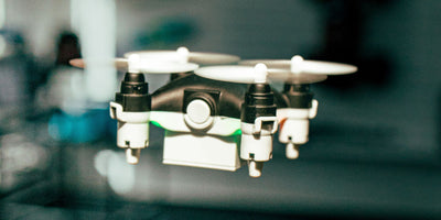 Sort Micro Drone i luften tæt på med grønt lys i undersiden
