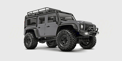 Sølvgrå Traxxas TRX-4M Land Rover Defender crawler i skala 1:18 set skråt forfra på hvid baggrund.