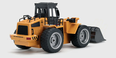 Gul fjernstyret gummiged med bevægelig skovl og grove dæk til leg i sandkassen.