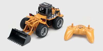 Gul fjernstyret gummiged med bevægelig frontskovl og terrængående dæk til udendørs leg.
